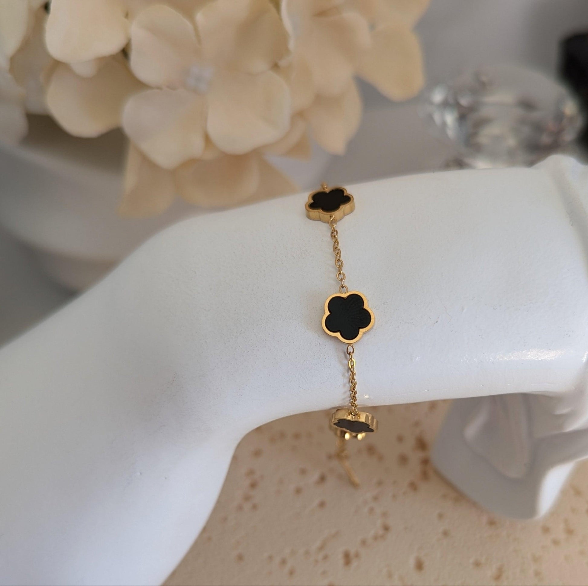 Gold-plated floral charm bracelet featuring black enamel flowers, waterproof and hypoallergenic with an adjustable chain.