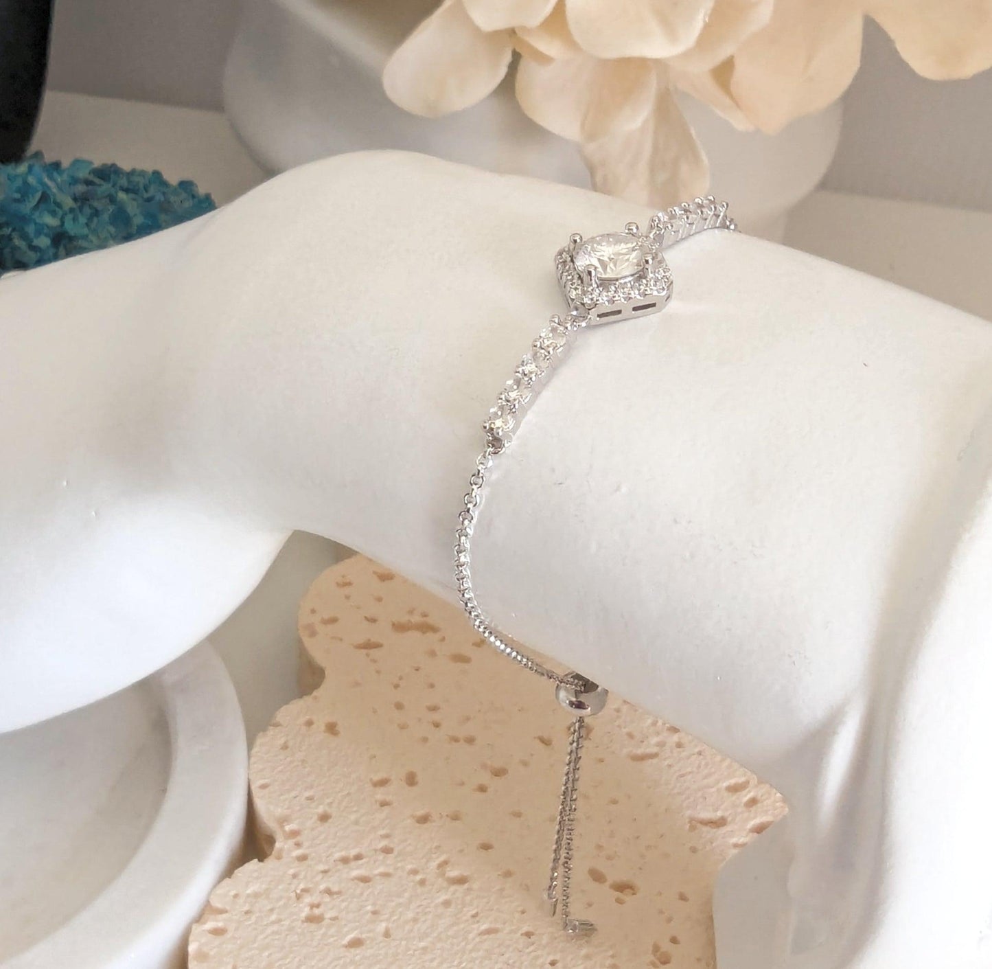 A delicate 1ct Moissanite Diamond Bracelet in 925 Sterling Silver, featuring a high-sparkle moissanite stone set in a halo design. The adjustable sliding clasp allows for a comfortable fit on 6cm - 9cm wrists. The bracelet is hypoallergenic, non-tarnish, and luxurious, displayed elegantly on a white jewelry stand with a soft, romantic backdrop.
A delicate 1ct Moissanite Diamond Bracelet in 925 Sterling Silver, featuring a high-sparkle moissanite stone set in a halo design. The adjustable sliding cla