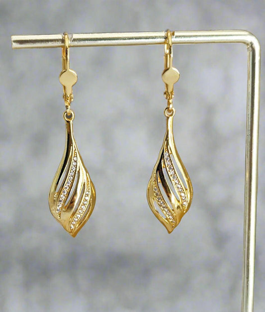 Close-up of a 14K gold plated sterling silver drop earring with a leaf-inspired design and sparkling cubic zirconia, worn on a black mannequin.