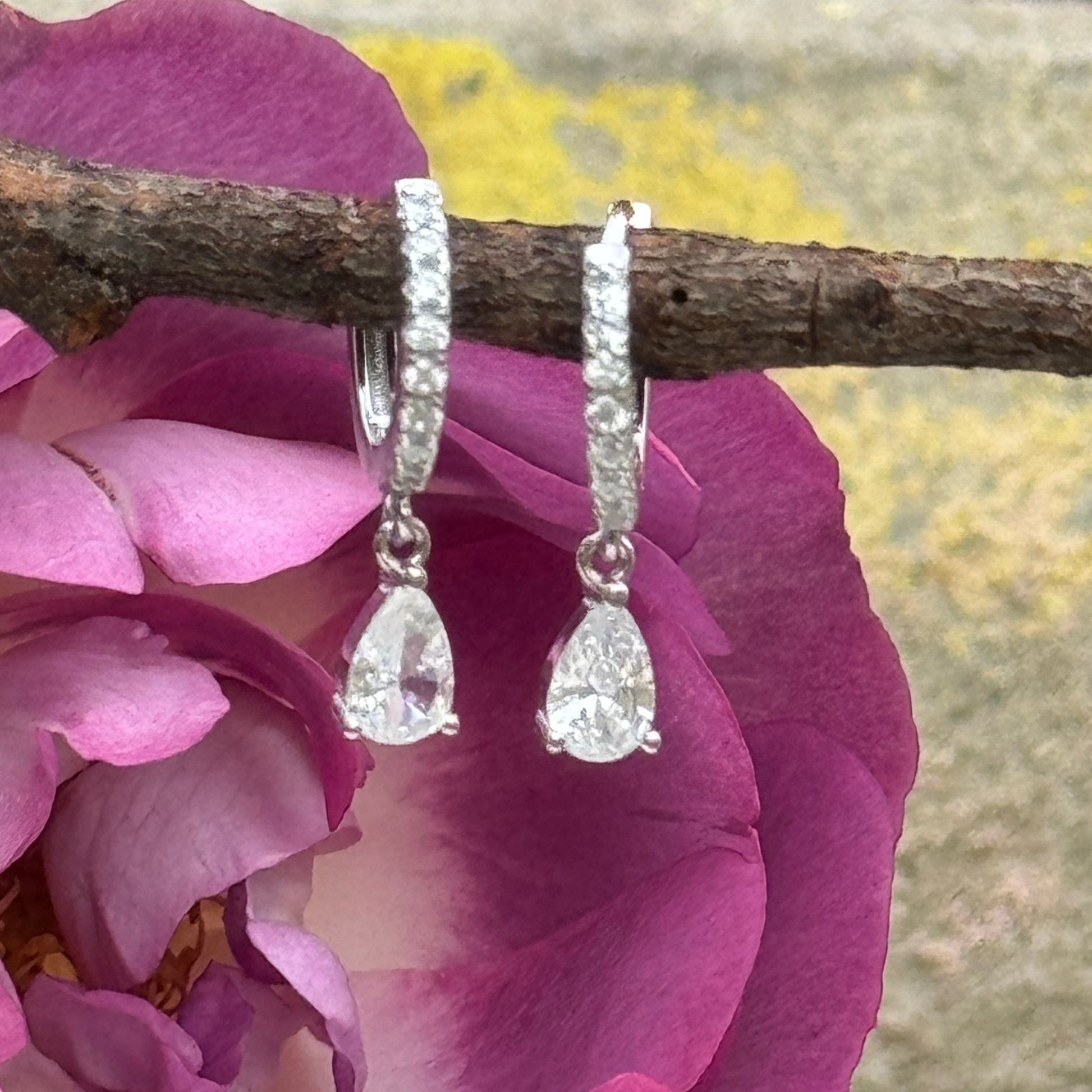 Sterling Silver CZ Drop Huggies with Rhinestone Accents hanging from a natural tree branch with a beautiful rose background
