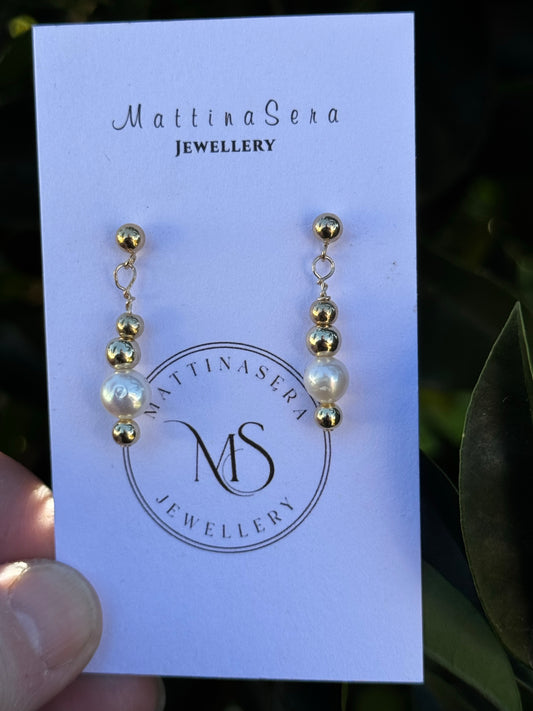 Pair of earrings on a Mattiasera Jewellery card held by a hand with a leafy background.