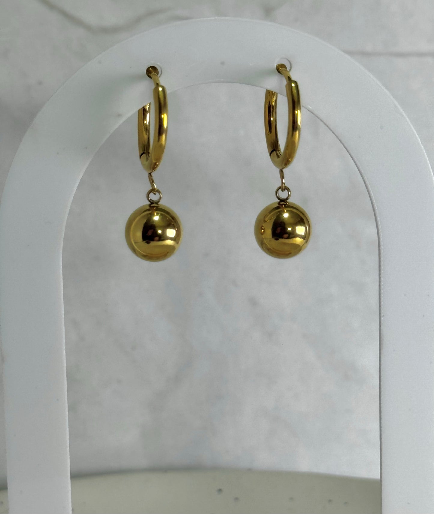 Gold hoop earrings with spherical charms on a white background