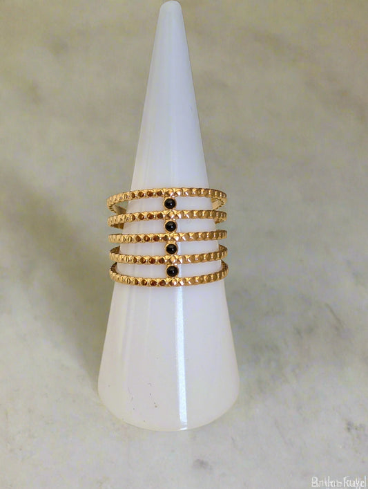 Adjustable wide gold ring with black enamel accents on ring display