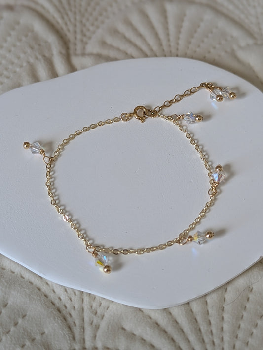 Gold bracelet with small beads on a white dish