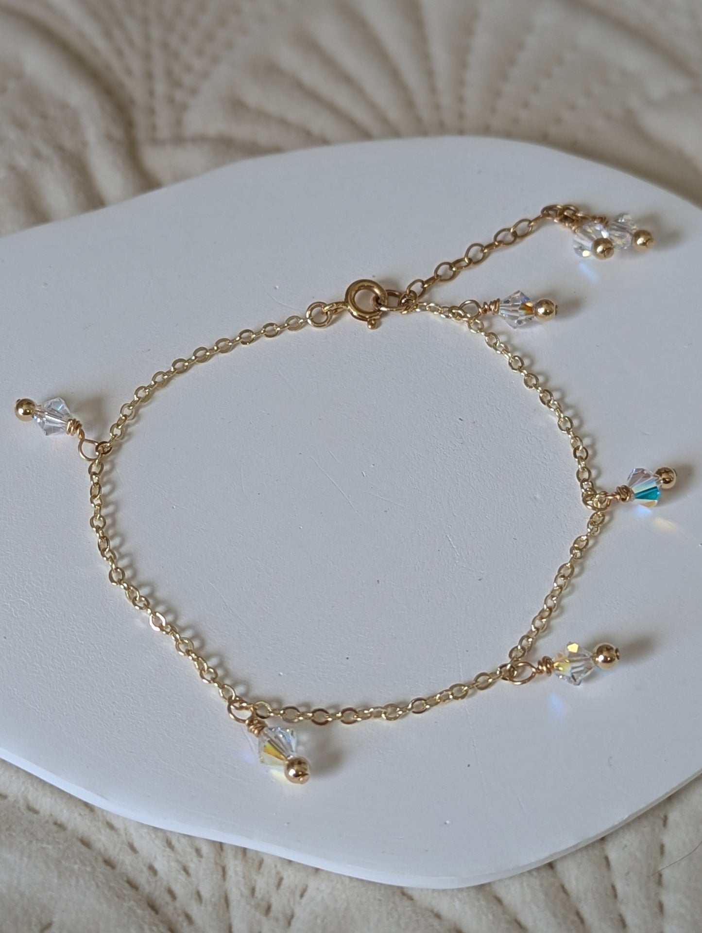 Gold bracelet with small beads on a white heart-shaped pad