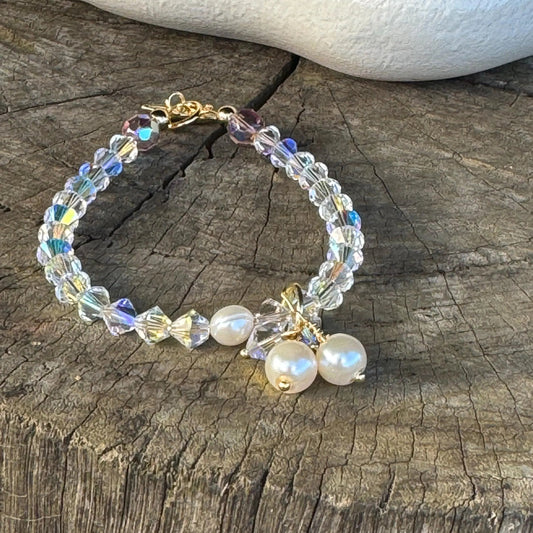 Crystal bracelet with pearls laying flat on a wooden background