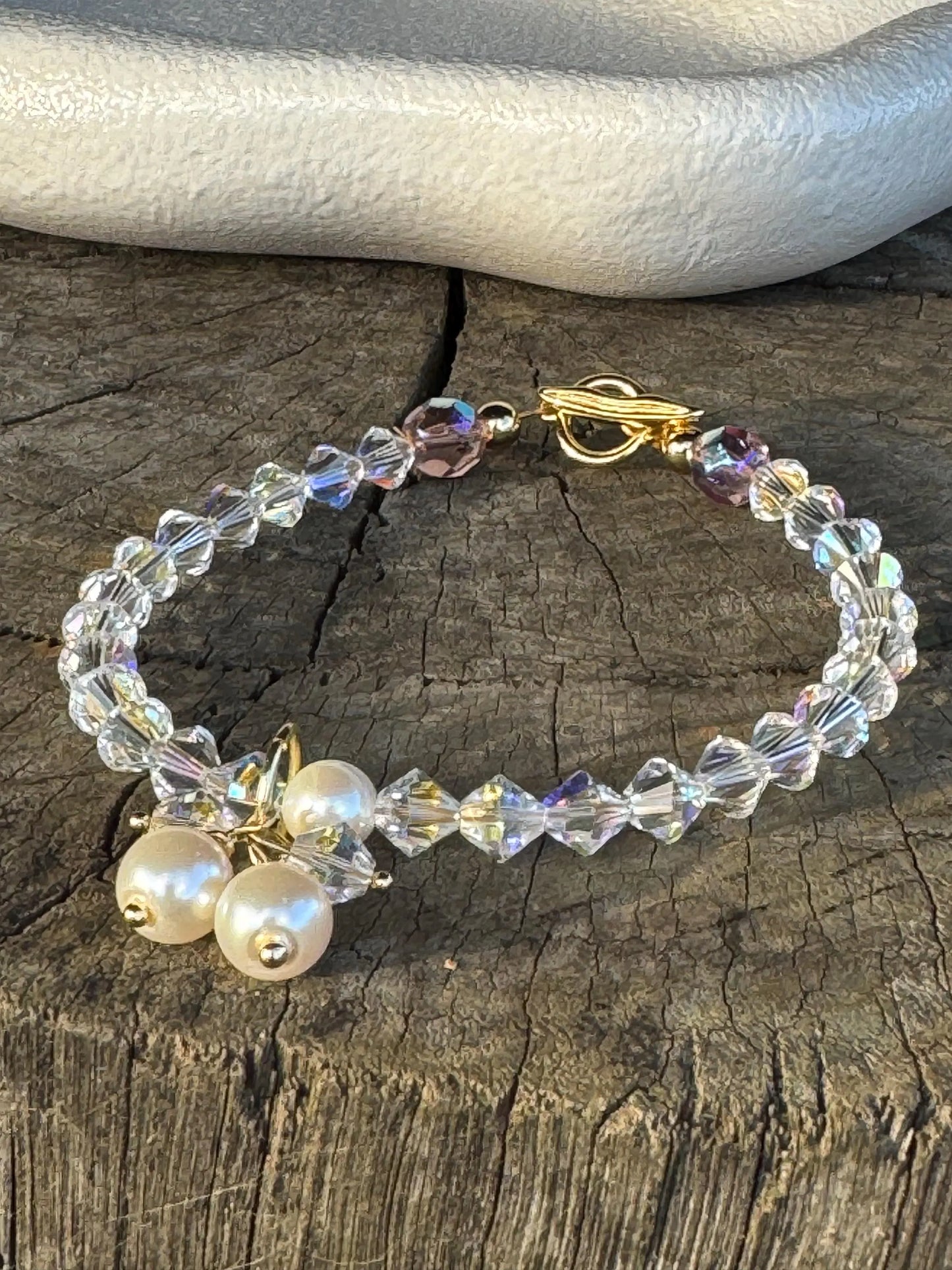 Bracelet with clear beads and pearl charms on a wooden surface