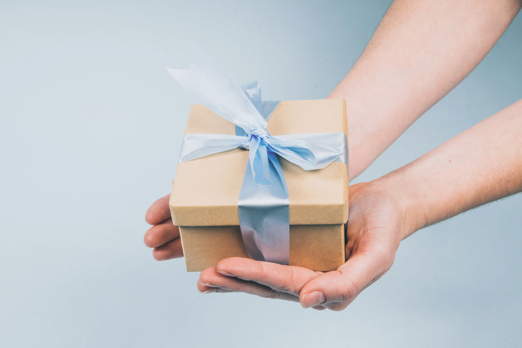a pair of hands holding a gift box with a blue ribbon.  Gift giving.
