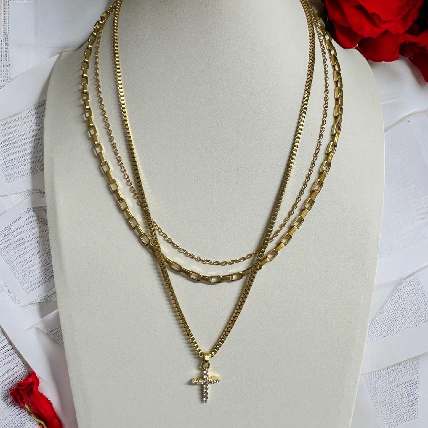 Close-up of triple layered gold necklace with cross pendant on display bust – waterproof, non-tarnish, 18K gold-plated chains in varying styles
