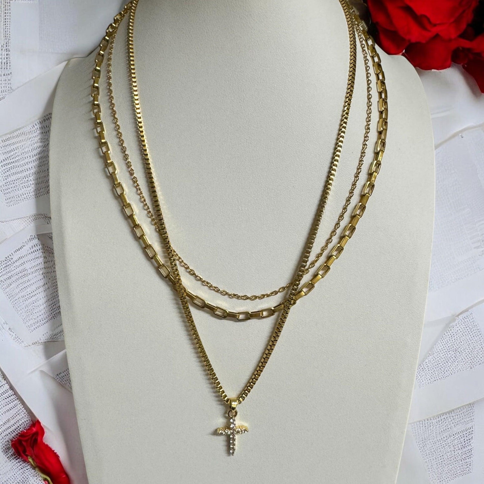 Close-up of triple layered gold necklace with cross pendant on display bust – waterproof, non-tarnish, 18K gold-plated chains in varying styles