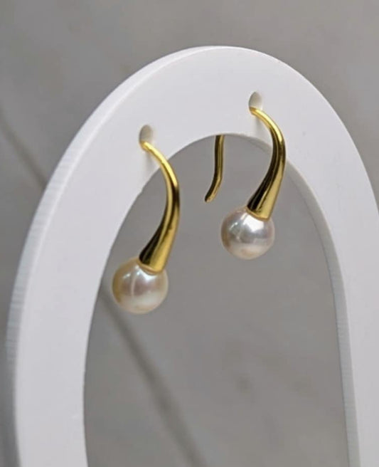 gold hook pearl earrings on white earring display