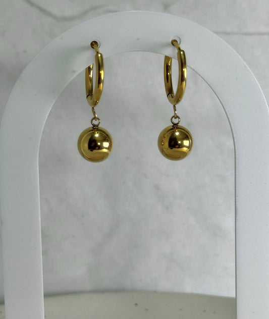 Gold hoop earrings with spherical charms on a white background
