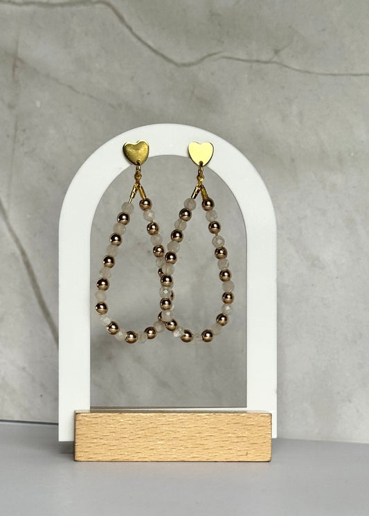 Pair of beaded earrings on a white arch stand against a gray background