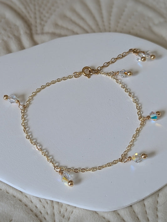Gold bracelet with small beads on a white heart-shaped pad